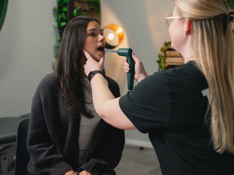 Eine Person erhält eine Munduntersuchung von einer Fachkraft in einer Klinik.