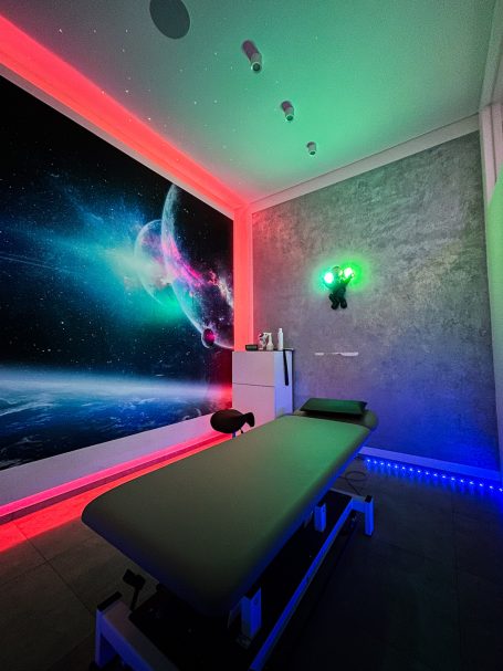 Behandlungsraum mit futuristischer Wandgestaltung und bunten LED-Lichtern.