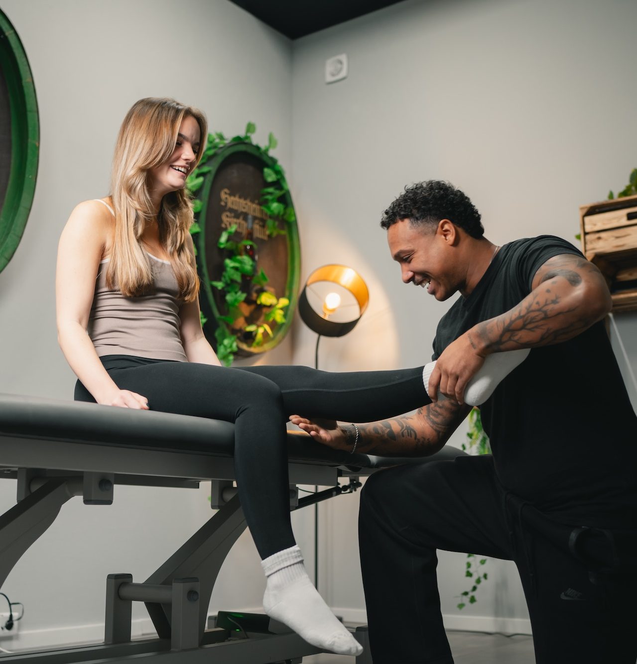 Physiotherapeut behandelt das Bein einer Patientin auf einer Liege.