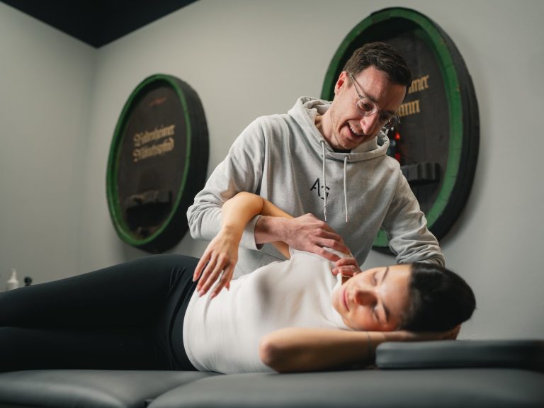 Eine Person erhält eine Behandlung auf einer Liege in einem modernen Therapieraum.